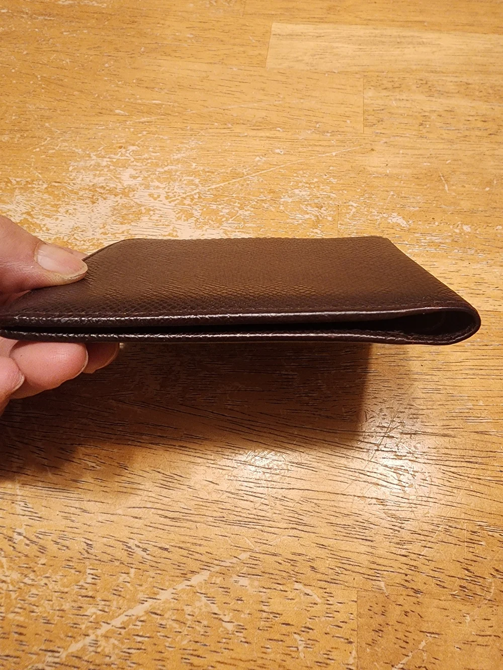 burgandy Louis Vuitton Taiga leather bifold wallet featuring a debossed LV
